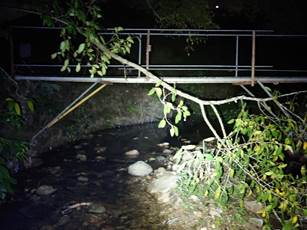 A bridge over a stream at night

Description automatically generated